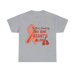 May include: A grey t-shirt with an orange ribbon and boxing gloves. The text on the shirt reads "In this family, no one fights alone."