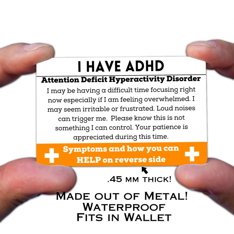 May include: A white card with orange accents reads "I HAVE ADHD Attention Deficit Hyperactivity Disorder" and includes information about the disorder. The card is made of metal, is waterproof, and is 0.45 mm thick. The card is held in a hand.