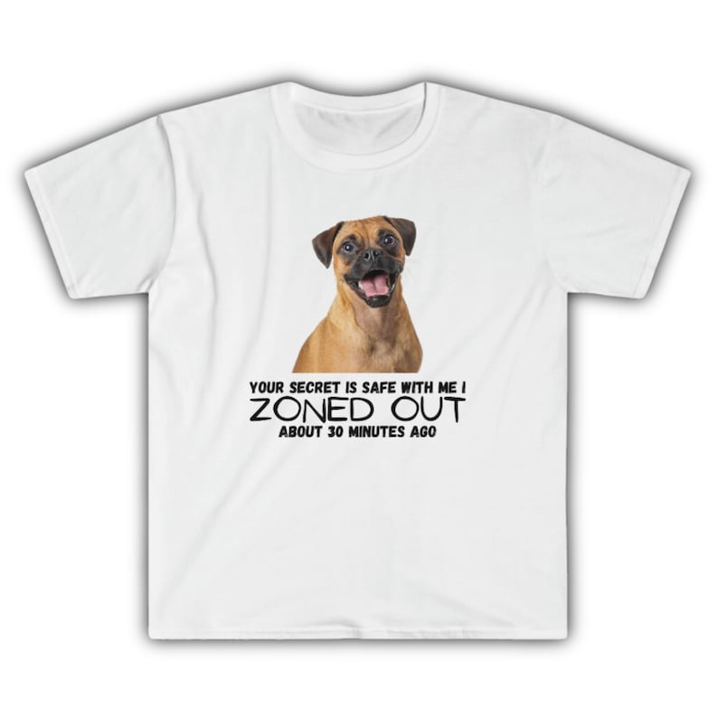 Pode incluir: Camiseta branca com um c&atilde;o castanho e branco nela. O texto "Your secret is safe with me I ZONED OUT about 30 minutes ago" est&aacute; impresso abaixo do c&atilde;o.