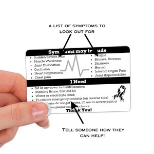 May include: A black and white card with a heart rate monitor graphic and the text "Symptoms may include" and "I Need". The card lists symptoms of a medical emergency and instructions for what to do if someone is experiencing these symptoms. The card also includes a zebra stripe pattern.