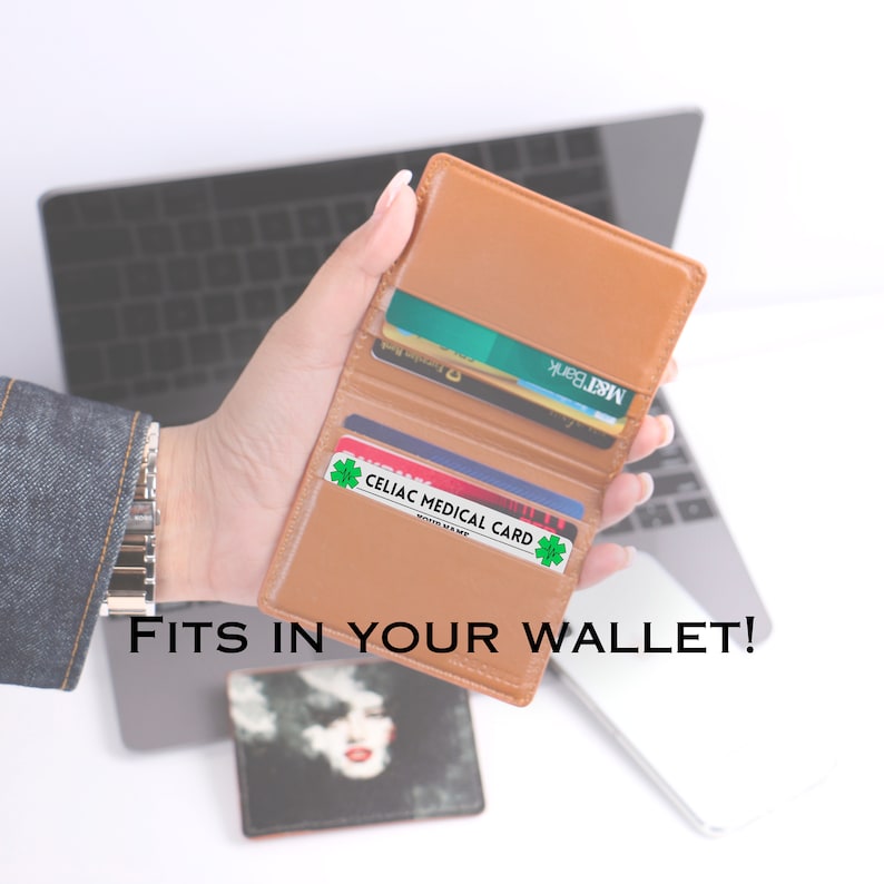May include: A brown leather wallet with a card that says "Celiac Medical Card" inside. The wallet is open and has several cards inside. The text "FITS IN YOUR WALLET!" is printed below the wallet.