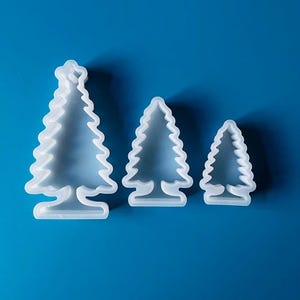 Peut inclure: Trois emporte-pièces en plastique blanc en forme de sapin de Noël de différentes tailles. Le plus grand emporte-pièce mesure environ 10 cm de haut, le moyen environ 7,5 cm et le plus petit environ 5 cm.