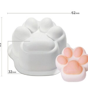 May include: White silicone mold shaped like a paw print. The mold is 6.2 cm wide and 5.8 cm tall. A pink paw print made with the mold is shown next to it.