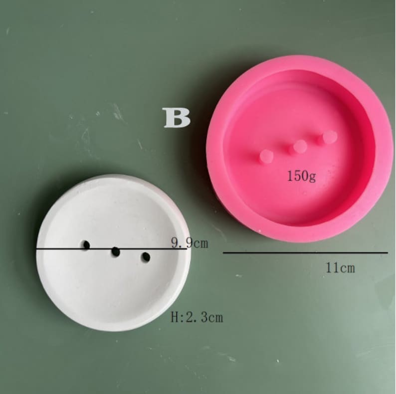 May include: Two round silicone molds for making concrete planters. The larger mold is pink and measures 11 inches in diameter. The smaller mold is white and measures 9.9 inches in diameter. Both molds have three holes in the bottom for drainage.