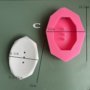May include: A white octagonal soap dish with three holes and a pink silicone mold of the same shape. The soap dish measures 9.1 inches wide, 2.85 inches high, and 13 inches long. The mold measures 11 centimeters wide and 15.5 centimeters high. The mold weighs 281 grams.