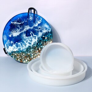 May include: Set of four round silicone molds for resin art projects. The molds are white and come in different sizes. The largest mold is 10 inches in diameter.