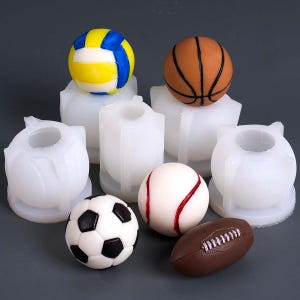 May include: A collection of sports-themed silicone molds featuring a volleyball, basketball, baseball, soccer ball, and football. The balls are in their respective colors and designs. The molds are white and in various shapes.