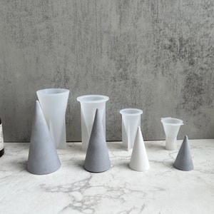 Può includere: Set di sei stampi in silicone per realizzare coni in cemento. Gli stampi sono trasparenti e disponibili in diverse dimensioni. I coni sono in cemento e sono in diverse tonalità di grigio e bianco.
