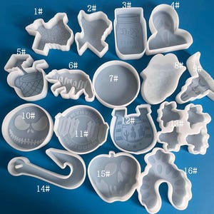 May include: A set of 16 silicone molds for resin casting. The molds are numbered 1 through 16 and feature various shapes, including a horseshoe, a skull, a fish, a bottle, a heart, and a Christmas tree.