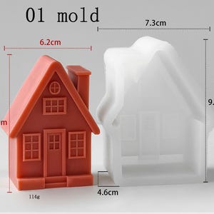 May include: A terracotta-colored house-shaped object next to a translucent white silicone mold. The house measures 6.2 cm wide by 8.4 cm high and weighs 114g. The mold measures 7.3 cm wide by 9.7 cm high and 4.6 cm deep. Text reads 01 mold.