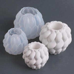 Puede incluir: Cuatro jarrones decorativos con diseño de pétalos. Dos son blancos y dos son de color azul translúcido. Los jarrones son de diferentes tamaños, con un borde festoneado. El diseño recuerda a una flor o alcachofa.