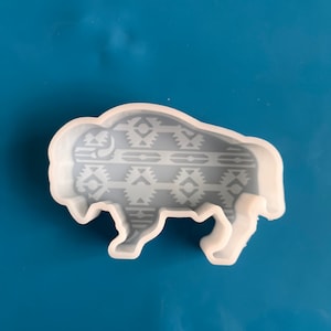 May include: White silicone mold shaped like a buffalo with a geometric pattern on the body.