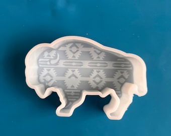 May include: White silicone mold shaped like a buffalo with a geometric pattern on the body.
