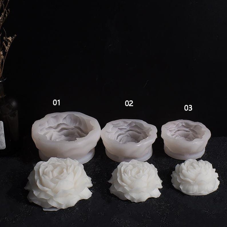 May include: Three white silicone molds in the shape of roses, numbered 01, 02, and 03. Below each mold is a corresponding white rose. The molds are for crafting or casting, and the roses are likely the finished product.