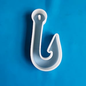 Puede incluir: Molde de plástico blanco en forma de anzuelo de pesca. El molde está diseñado para ser utilizado para la fabricación de artesanías de resina.