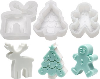Op de afbeelding: Set van drie siliconen mallen voor het maken van kerstthema-traktaties. De mallen zijn wit en bevatten een rendier, een kerstboom en een gingerbread man.