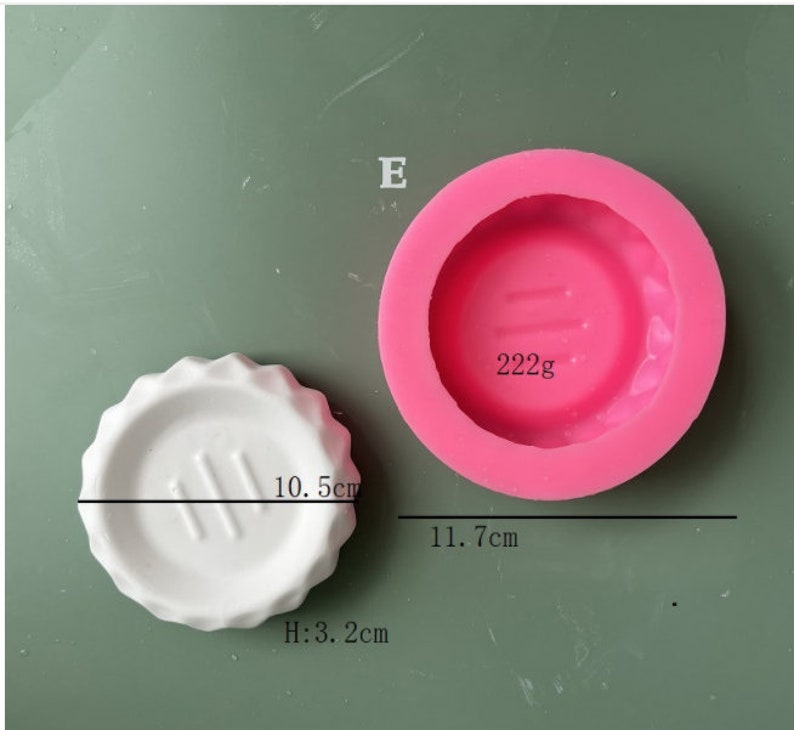 May include: Pink silicone mold for making a round cake or dessert. The mold is 11.7 cm in diameter and has a 10.5 cm diameter circle in the center. The mold is 3.2 cm tall. The mold is labeled "222g".
