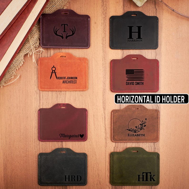 May include: Ten different leather horizontal ID card holders with various designs and text. The designs include a deer antler, a compass, a US flag, a floral wreath, a letter H, and the letters HRD and HTK. The text includes names, titles, and initials.