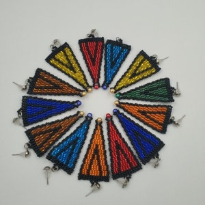May include: A set of 12 beaded triangle earrings in various colors, including red, orange, yellow, green, blue, and purple. The earrings are all made with small, colorful beads and have a silver hook.