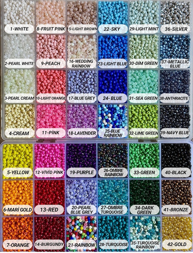 May include: A clear plastic organizer filled with small, colorful beads. The beads are arranged in labeled compartments, showcasing a variety of colors including white, pink, blue, green, and gold. The labels include the color names and numbers.