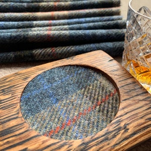 Pode incluir: Um descanso de copo de madeira com um inserto redondo de tecido xadrez azul, verde e vermelho. O descanso de copo &eacute; feito de madeira reciclada e tem um acabamento natural e r&uacute;stico.