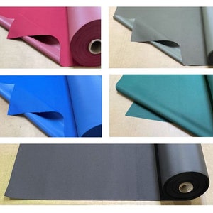 May include: Four rolls of fabric in different colors: red, blue, green, and gray. The fabric is folded and rolled up.