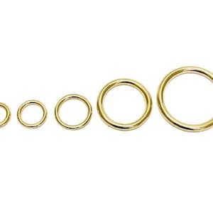 May include: A set of five gold-coloured metal rings of varying sizes. The rings are smooth and round.