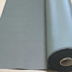 May include: A roll of dark green fabric with a textured surface. The fabric is rolled up and secured with a black band.