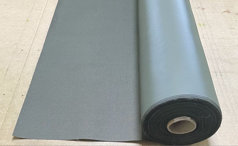 May include: A roll of dark green fabric with a textured surface. The fabric is rolled up and secured with a black band.