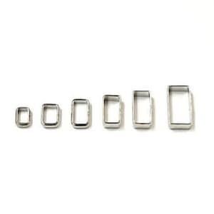 May include: Set of six silver metal rectangular rings of varying sizes.