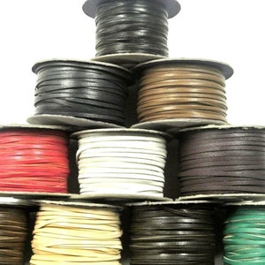 May include: Spools of leather cord in various colours, including black, brown, red, white, beige, green, and dark brown. The cords are wound around spools with a white background.