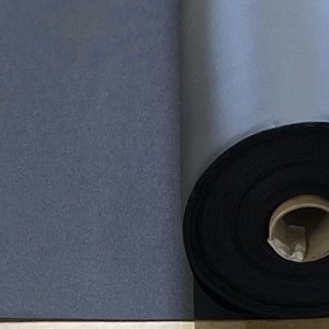 May include: A roll of black fabric, likely for crafting or upholstery, is partially unrolled on a light brown surface.