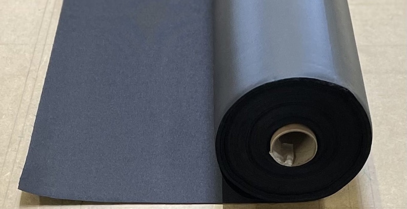 May include: A roll of black fabric, likely for crafting or upholstery, is partially unrolled on a light brown surface.
