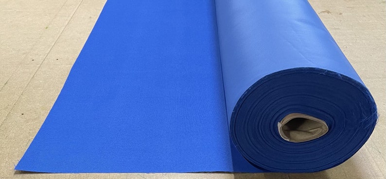 May include: A roll of bright blue fabric, unfurled on a brown surface. The fabric is smooth and appears to be a woven material.