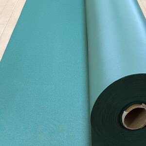 May include: A roll of teal green fabric, partially unrolled, showing the fabric's texture.