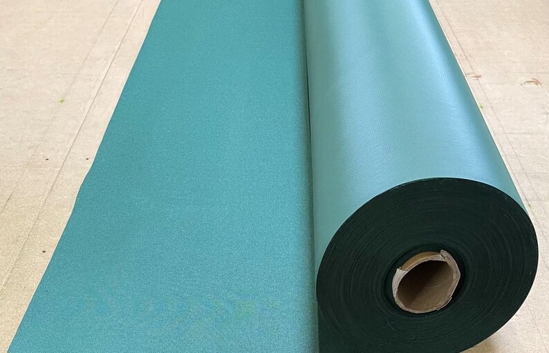 May include: A roll of teal green fabric, partially unrolled, showing the fabric's texture.