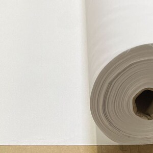 May include: A white roll of fabric, unfurled to show the texture of the material.