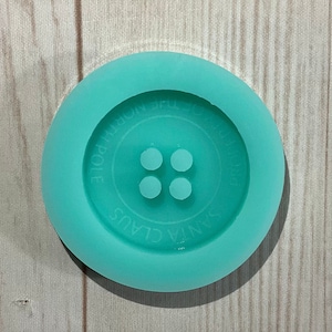 May include: A teal blue silicone mold for making a four-hole button. The mold has the words "Santa Claus" and "Homemade" written on it.
