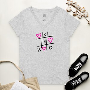 May include: Gray V-neck t-shirt with a black and pink graphic of a tic-tac-toe board with hearts replacing the X's and O's.
