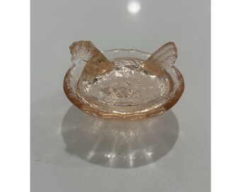 Gallina vintage in vetro rosa dell'epoca della Grande Depressione sul nido