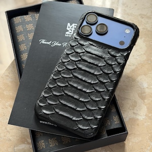 May include: Black textured phone case with a scale-like pattern, displayed on a black box with the text "Thank You". The phone case has a blue camera area and is shown with a matching patterned box.