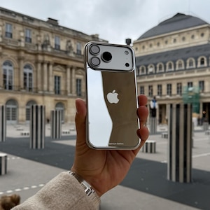 Puede incluir: Una funda plateada para iPhone con parte trasera reflectante, con el logotipo de Apple. La funda tiene un marco met&aacute;lico y un recorte para la c&aacute;mara. Las palabras "Platinum Edition" est&aacute;n impresas en la parte inferior.