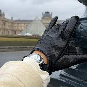 May include: A set of three ceramic mugs with a speckled, matte finish. The mugs are in shades of cream, light gray, and dark gray. Each mug has a simple, minimalist design and a rounded handle. The mugs are likely for coffee or tea.