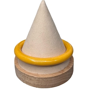 May include: A bright yellow bangle bracelet displayed on a beige cone-shaped jewelry holder. The bracelet is a solid, smooth band of color. The holder sits on a round, wooden base, creating a simple, elegant presentation.