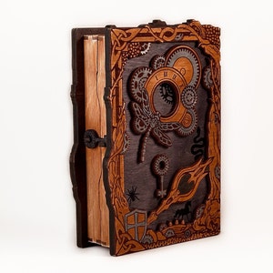 May include: A wooden book box with intricate carvings and a steampunk design. The box features a dragonfly, gears, and a keyhole. The box is made of dark brown wood with a light brown interior.