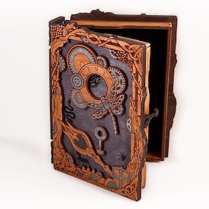 May include: A wooden box with a hinged lid, intricately carved with a steampunk design. The lid features a dragonfly, gears, and a clock face. The box is painted in shades of brown and gray.