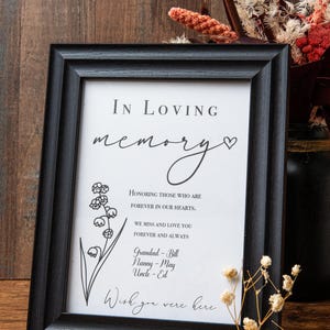 May include: A black framed print with the text "IN LOVING memory" and a small heart. The print also includes a floral illustration and the text "HONORING THOSE WHO ARE FOREVER IN OUR HEARTS. WE MISS AND LOVE YOU FOREVER AND ALWAYS Grandad - Bill Nanny - May Uncle - Ed Wish you were here"