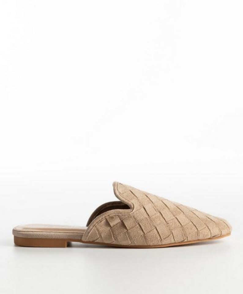 May include: A single beige woven mule slipper with a pointed toe. The shoe has a low heel and a slip-on design. The upper features a basketweave pattern. The shoe is set against a white background.