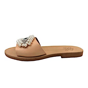 May include: A pair of light brown leather sandals with a pearl and evil eye embellishment.