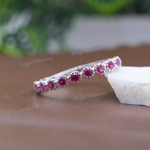 Könnte beinhalten: Ein silberner Bandring mit einer Reihe kleiner rosafarbener Edelsteine.